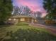 Charming single-story brick home with a well-manicured lawn and attached two car garage at dusk at 50 Yarrow St, Lakewood, CO 80226