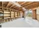 Unfinished attic featuring exposed beams, shelving, and access to a balcony with natural light at 6348 S Independence St, Littleton, CO 80123