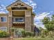 Condo exterior with stacked stone and siding, balcony, stairs, landscaping, and blue sky at 8726 S Kline St # A208, Littleton, CO 80127