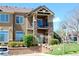 Tan condo building exterior with stone accents, balcony, and stairway with lush landscaping and parking at 8726 S Kline St # A208, Littleton, CO 80127