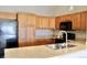 Kitchen showcasing wooden cabinets, black appliances, and a practical layout at 8726 S Kline St # A208, Littleton, CO 80127