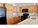 Functional kitchen featuring wooden cabinetry, black appliances, and ample counter space at 8726 S Kline St # A208, Littleton, CO 80127
