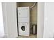 A stacked white washer and dryer with metal trash can is in the laundry closet at 8726 S Kline St # A208, Littleton, CO 80127