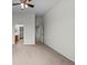 A bright bedroom with neutral walls and carpet, featuring a ceiling fan and adjoining bathroom at 7713 S Zante Ct, Aurora, CO 80016