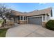 Well-maintained home exterior featuring a gray garage door, stone accents, and manicured landscaping at 7713 S Zante Ct, Aurora, CO 80016