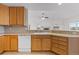 Functional kitchen featuring wood cabinetry, a white dishwasher, and views into the living room at 7713 S Zante Ct, Aurora, CO 80016