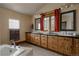 Bathroom with tiled shower, dual sinks, dark countertops and wood cabinets offers functional elegance at 1260 Hudson St, Denver, CO 80220