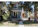 Charming two-story home with a balcony and a walkway leading to the front door surrounded by mature trees at 1260 Hudson St, Denver, CO 80220