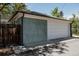 Detached two car garage with white door, blue-gray siding, and an adjacent wooden fence at 1260 Hudson St, Denver, CO 80220