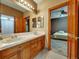 Bathroom with double sinks, wood cabinets, and a view into an adjacent bedroom at 6533 S Quemoy Way, Aurora, CO 80016