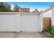 A detached single-car garage features a white paneled door, corrugated roof, and white painted siding at 122 N Logan St, Denver, CO 80203