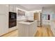 Bright eat-in kitchen features white cabinets, an island cooktop, stainless refrigerator, and wooden floors at 20 Scott Dr, Broomfield, CO 80020