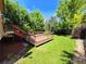 Green backyard featuring a wooden deck with brown railings, surrounded by mature trees and lush green grass at 8772 S Carr Way, Littleton, CO 80128