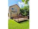 Exterior view of the home highlighting the deck, manicured lawn, mature trees, and architectural details at 8772 S Carr Way, Littleton, CO 80128