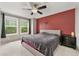 A cozy main bedroom has a decorative red accent wall, a ceiling fan, and lots of natural light at 9503 Longs Peak Dr, Commerce City, CO 80640
