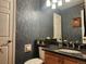 Stylish half bathroom with unique wallpaper, granite countertop, and decorative mirror at 2533 W 110Th Ave, Westminster, CO 80234