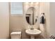 This half bath features a pedestal sink, oval mirror, and a window with blinds at 18809 E 66Th Ave, Denver, CO 80249