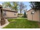 Spacious backyard featuring a lush lawn, mature trees, garden shed, and sidewalk connecting the home at 1090 E 3Rd Ave, Denver, CO 80218
