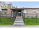 Inviting brick home featuring a secure metal fence, covered porch entry, and flower-filled planters flanking the steps at 1090 E 3Rd Ave, Denver, CO 80218