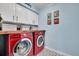 Bright laundry room with overhead cabinets, wooden countertop, stylish tile floors, and red washer and dryer set at 14332 Craftsman Way, Broomfield, CO 80023