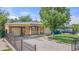 Charming single-story home with a covered porch, carport and black metal fence at 6871 Locust St, Commerce City, CO 80022