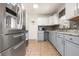 Well-lit kitchen with stainless steel appliances, gray cabinets, and tile backsplash at 6871 Locust St, Commerce City, CO 80022
