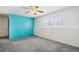 Finished basement with gray carpet, blue accent wall, ceiling fan, and bright natural light from window at 12065 E Kentucky Ave, Aurora, CO 80012