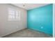 Bedroom featuring a modern grey carpet, a bright blue accent wall, and a window with white shutters at 12065 E Kentucky Ave, Aurora, CO 80012
