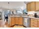 Well-lit kitchen with wooden cabinets, a modern faucet, and hardwood floors, adjacent to the dining area at 12420 E Iliff Pl, Aurora, CO 80014