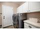 Functional laundry room with ample cabinet space, stainless steel washer and dryer, and tile flooring for easy maintenance at 2749 Pemberly Ave, Highlands Ranch, CO 80126