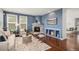 Inviting living room features a stone fireplace, wood floors, and stylish blue accent wall with built-in shelving at 2749 Pemberly Ave, Highlands Ranch, CO 80126
