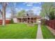 Well-maintained exterior of a home featuring a grassy front yard, covered patio, decorative windmill, and mature trees at 2989 S Corona St, Englewood, CO 80113