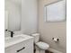 Half bathroom featuring white vanity, black fixtures, modern toilet, and window at 3017 W 53Rd Ave, Denver, CO 80221