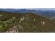 Scenic aerial view of a property perched atop a hill, surrounded by lush forest and distant mountains at 4923 Snowberry Ln, Evergreen, CO 80439