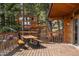 Inviting wooden deck with outdoor seating and scenic views of the surrounding woods and neighboring property at 4923 Snowberry Ln, Evergreen, CO 80439