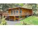 A-frame home with expansive wooden deck and matching wood siding surrounded by green grass and pines at 4923 Snowberry Ln, Evergreen, CO 80439