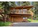Charming two-story home with wood exterior and large deck surrounded by trees at 4923 Snowberry Ln, Evergreen, CO 80439