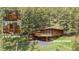 Scenic home with a large deck and wood accents surrounded by lush greenery and mature trees at 4923 Snowberry Ln, Evergreen, CO 80439