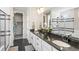 Modern bathroom featuring dual sinks, black granite countertops, a glass-enclosed shower, and a large mirror at 20783 E 50Th Pl, Denver, CO 80249