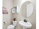 Chic half bathroom with a pedestal sink, toilet, decorative mirror, and stylish wall decor at 20783 E 50Th Pl, Denver, CO 80249