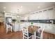 Well-lit open kitchen with granite countertops, white cabinetry, stainless steel appliances, and an island with bar seating at 20783 E 50Th Pl, Denver, CO 80249