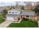 Two-story home featuring brick and siding, a two-car garage, mature trees, and landscaping, aerial view at 9340 W Burgundy Ave, Littleton, CO 80123