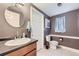 Cozy bathroom features a wood vanity, round mirror, toilet, and a window with a curtain at 10890 Stuart Ct, Westminster, CO 80031