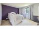 Serene bedroom features a purple accent wall, white linens, a large window, and carpeting at 10890 Stuart Ct, Westminster, CO 80031