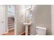 Neat powder room featuring pedestal sink, modern light fixture and toilet; stairs in background at 5640 S Marshall St, Denver, CO 80123