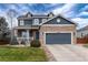 Beautiful two-story home featuring a stone facade, blue siding, covered porch, and well-manicured lawn at 14669 Eagle River Run, Broomfield, CO 80023