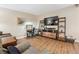 Well-lit living room area with wooden floors, featuring a large TV, desk and shelving unit at 9625 E Center Ave # 5D, Denver, CO 80247