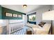 Charming Bedroom featuring a white crib, accent wall, and a comfortable chair by the window at 982 E 130Th Cir, Thornton, CO 80241