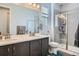 Well-lit bathroom with a double sink vanity, tile floors, and a glass-enclosed shower for a clean aesthetic at 9679 Waco St, Commerce City, CO 80022