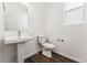 Bright half bathroom with modern pedestal sink, wood-look floors, and a window for natural light at 3639 Recess Ln, Castle Rock, CO 80108